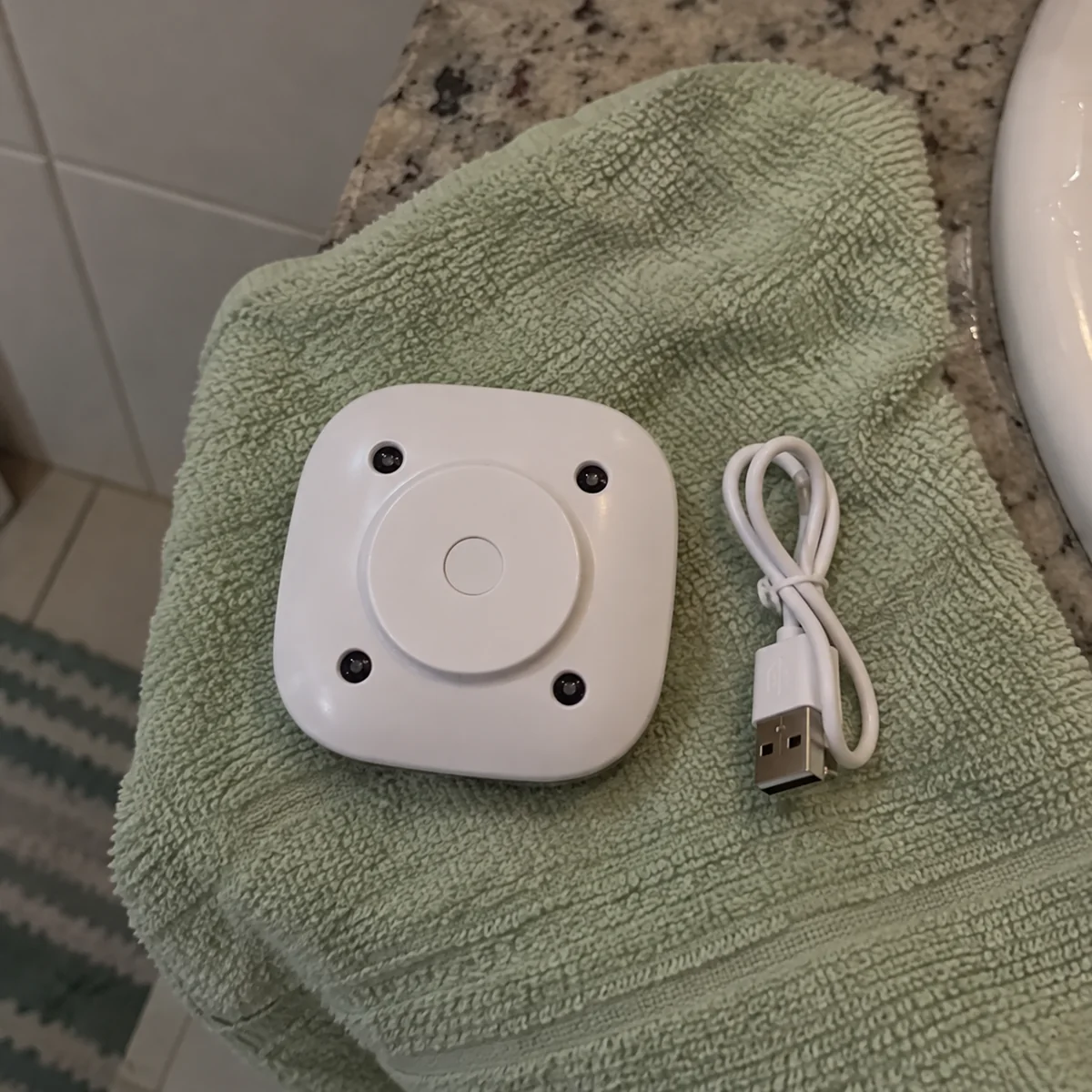 Cena ilustrativa: aparelho branco e cabo USB sobre uma toalha